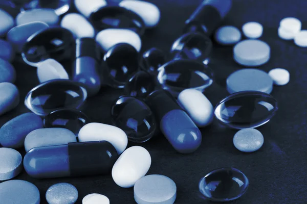 Ассортимент таблеток, таблеток и капсул в синем свете — стоковое фото