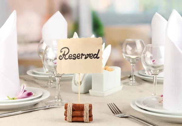 Reserved sign on restaurant table with empty dishes and glasses — Stock Photo, Image