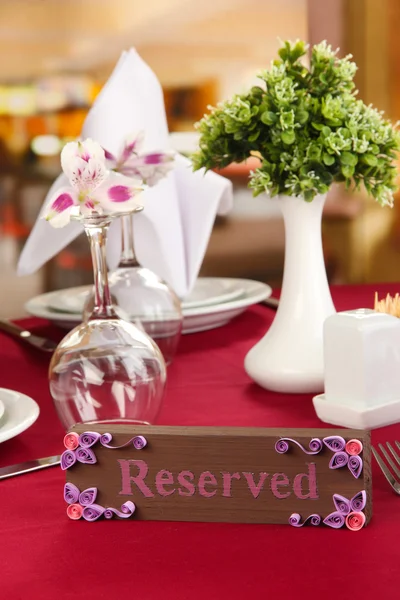 Reserved sign on restaurant table with empty dishes and glasses — Stock Photo, Image