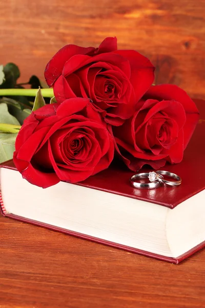 Anneaux de mariage sur bible avec des roses sur fond en bois — Photo