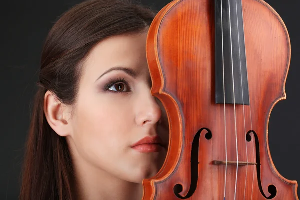 Bella ragazza con violino su sfondo grigio — Foto Stock