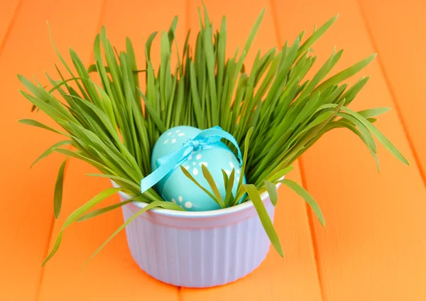 Uovo di Pasqua in ciotola con erba su tavolo di legno arancione da vicino — Foto Stock