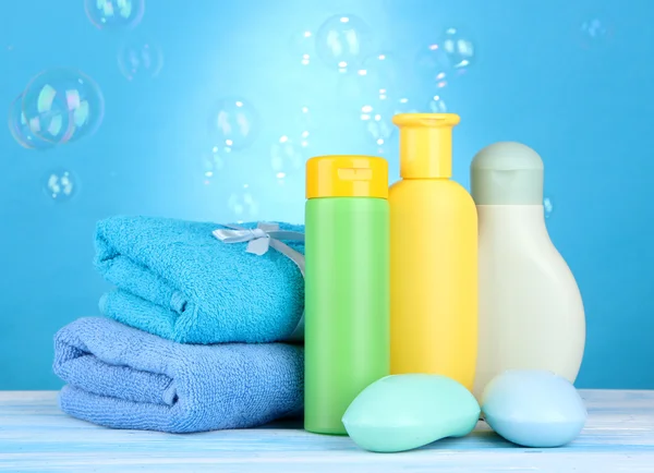Baby cosmetica, handdoeken en zeep op houten tafel, op blauwe achtergrond — Stockfoto