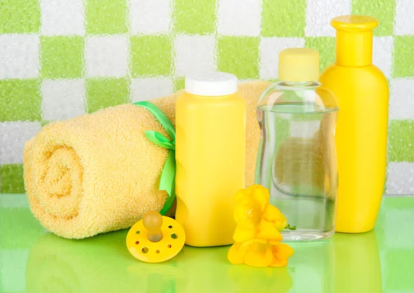 Baby cosmetics and towel in bathroom on green tile wall background — Stock Photo, Image