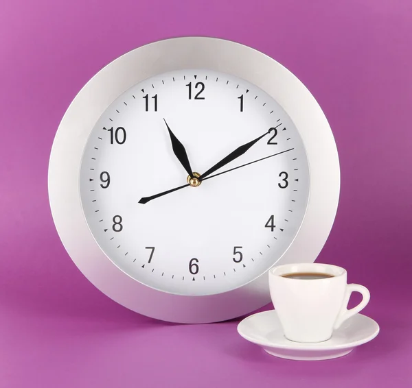 Cup coffee and clock on purple background — Stock Photo, Image