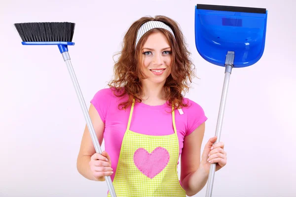 Young housewife with broom and dustpan on grey background — Stock Photo, Image