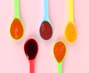 Bebek püresi pembe bir arka plan üzerine kaşık içinde