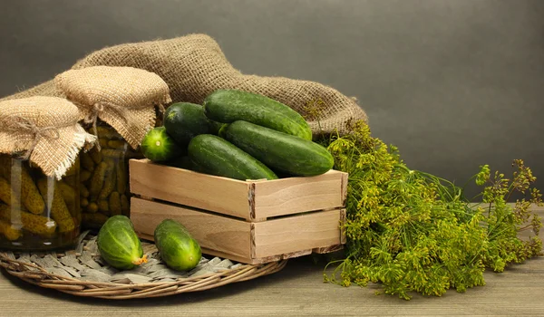 Färska gurkor i trälåda, pickles och dill, på grå bakgrund — Stockfoto