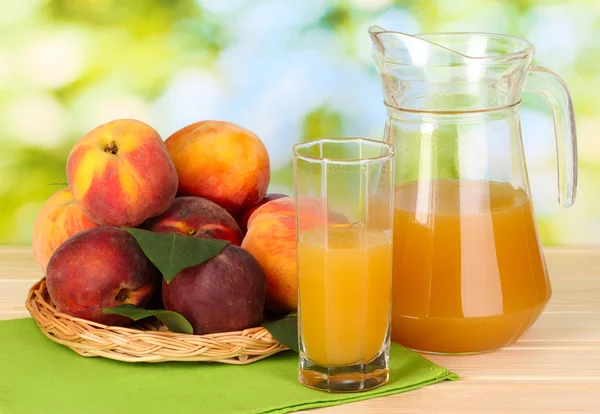 Спелые персики и сок на деревянном столе на естественном фоне — стоковое фото