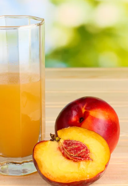 Ripe peaches and juice close-up on wooden table on natural background — Stock Photo, Image