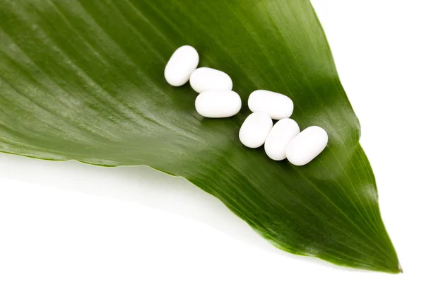 Tabletten op groene blad geïsoleerd op wit — Stockfoto