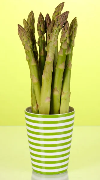 Verse asperges in kleurrijke pot op groene achtergrond — Stockfoto