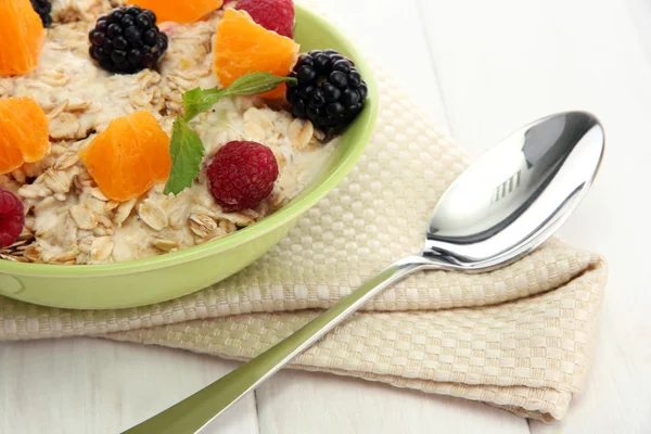 Tasty oatmeal with berries and fruits, on white wooden table — Stock Photo, Image