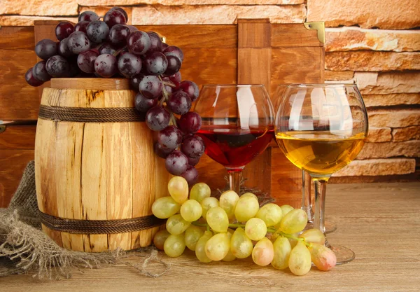 Composition du vin, boîte et raisins sur tonneau en bois sur table sur fond de mur de briques — Photo