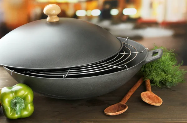 Černý pánev wok a zeleniny na kuchyňský dřevěný stůl, zblízka — Stock fotografie