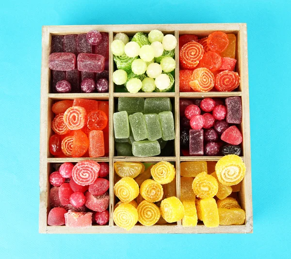 Multicolor candies in wooden box, on color background — Stock Photo, Image