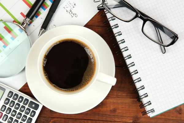 Xícara de café na mesa de trabalho coberto com documentos de perto — Fotografia de Stock