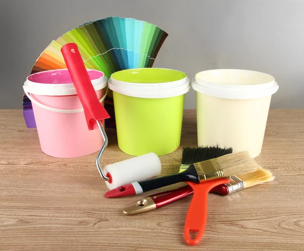 Schilderen van potten, verfborstels en gekleurde stalen op houten tafel op grijze achtergrond — Stockfoto