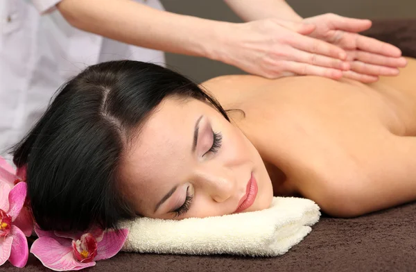 Schöne junge Frau im Wellness-Salon bekommt Massage mit Wellness-Steinen, auf dunklem Hintergrund — Stockfoto