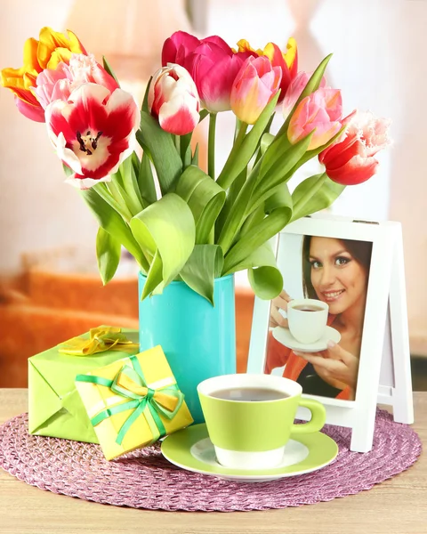 Belles tulipes dans un seau avec des cadeaux et une tasse de thé sur la table dans la chambre — Photo