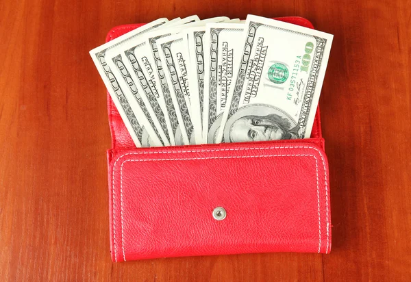 Purse with hundred dollar banknotes, on wooden background — Stock Photo, Image