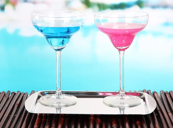 Glasses of cocktails on table near pool — Stock Photo, Image