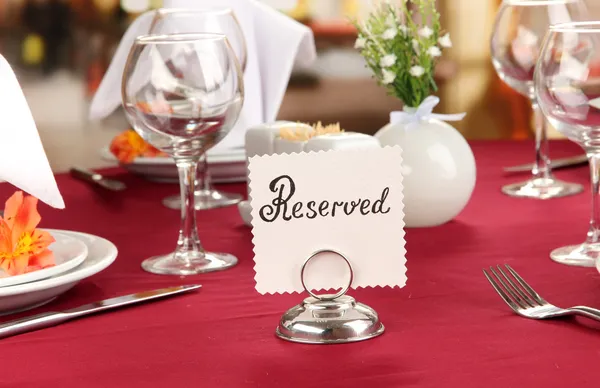 Зарезервированный знак на столе ресторана с пустыми блюдами и стаканами — стоковое фото