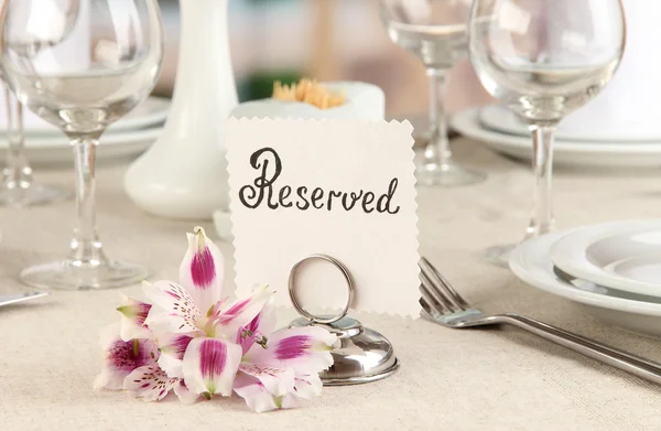 Reserved sign on restaurant table with empty dishes and glasses — Stock Photo, Image