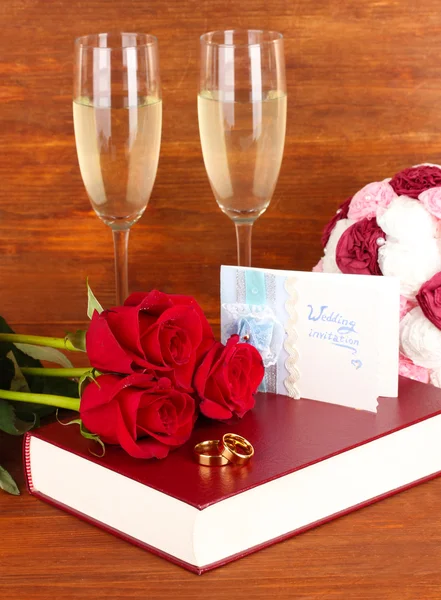 Cincin pernikahan pada Alkitab dengan mawar dan gelas sampanye di latar belakang kayu — Stok Foto