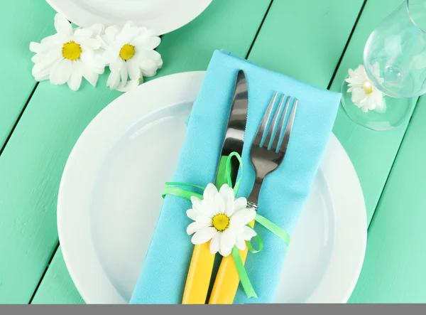 Knife and fork wrapped in napkin, on plate, on color wooden background — Stock Photo, Image
