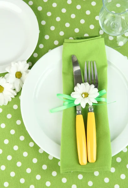 Нож и вилка, завернутые в салфетку, на тарелке, на фоне цветной скатерти — стоковое фото