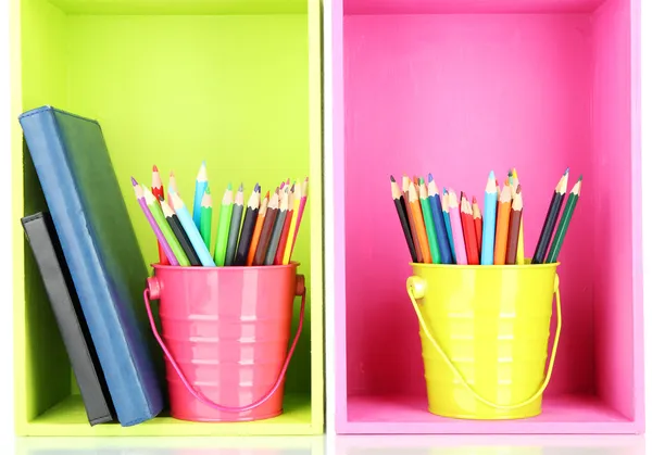 Barevné tužky v kbelíky s zapisování na policích — Stock fotografie