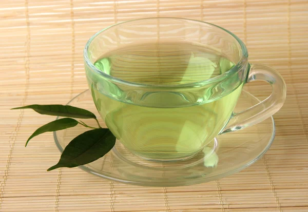 Taza transparente de té verde en estera de bambú, de cerca — Foto de Stock