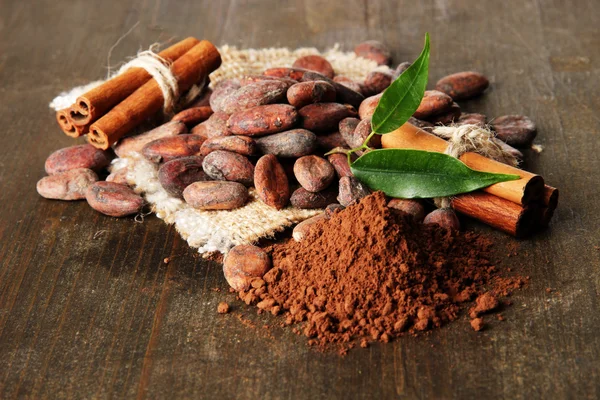 Frijoles de cacao, cacao en polvo y especias sobre fondo de madera —  Fotos de Stock