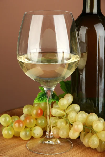 Composition bouteille de vin, verre de vin blanc, raisin sur tonneau en bois, sur fond de couleur — Photo