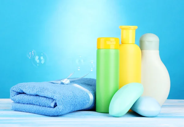 Cosmetici per bambini, asciugamani e sapone su tavolo di legno, su sfondo blu — Foto Stock