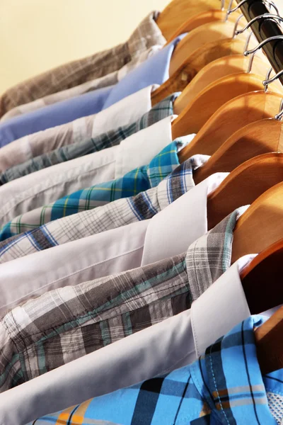 Men's shirts on hangers on beige background — Stock Photo, Image