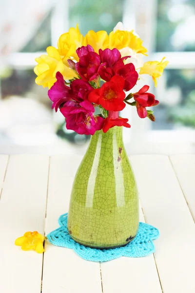 ウィンドウの背景に木製のテーブルの上の青い花瓶のフリージアの美しい花束 — ストック写真