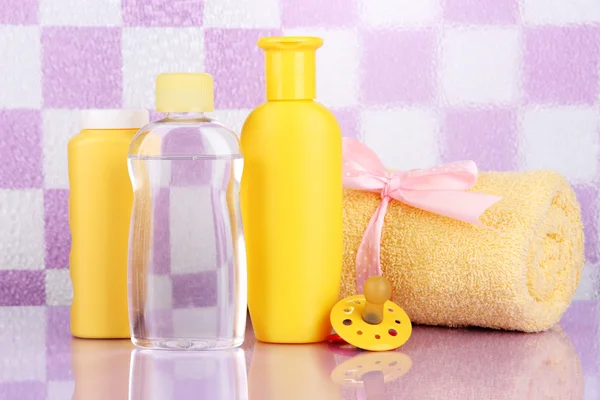 Bébé cosmétique et serviette dans la salle de bain sur fond de mur de tuiles violettes — Photo