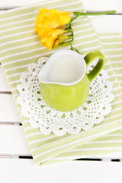 Groene kruik met melk op servet op houten picknick tafel close-up — Stockfoto