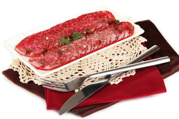 Salame saporito su piatto su tovagliolo isolato su bianco — Foto Stock