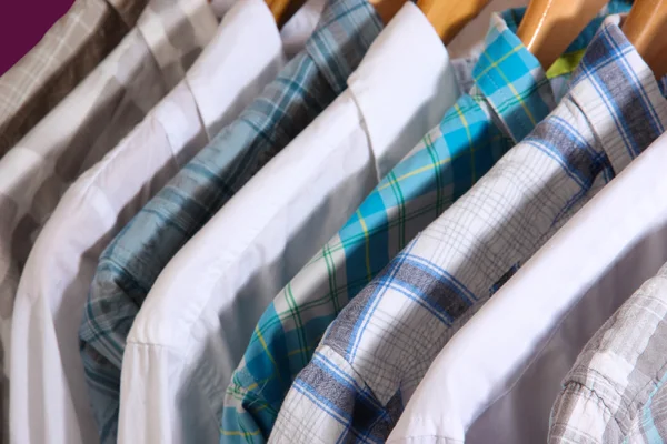 Men's shirts on hangers on purple background — Stock Photo, Image