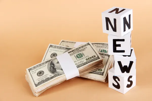 ホワイト ペーパー キューブ ベージュ色の背景上でお金で「ニュース」というラベルの付いた — ストック写真