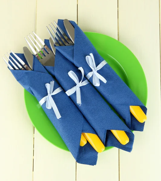 Tenedores y cuchillos envueltos en servilletas de papel azul, sobre fondo de madera de color —  Fotos de Stock