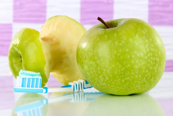 Äpplen med en tandborste på hyllan i badrummet — Stockfoto