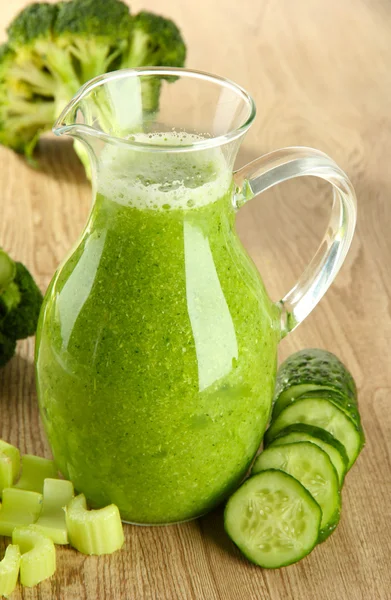 Glass pitcher of green vegetable juice on wooden background — Stock Photo, Image