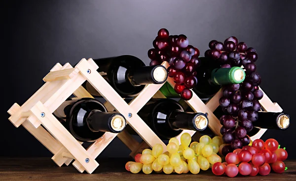 Botellas de vino colocadas sobre soporte de madera sobre fondo gris — Foto de Stock