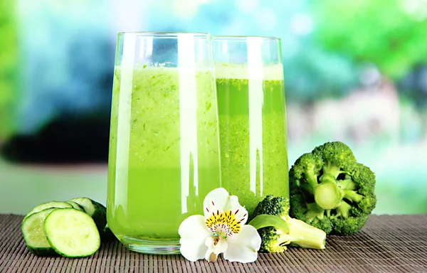 Bicchieri di succo vegetale, su tappetino di bambù, su fondo verde — Foto Stock