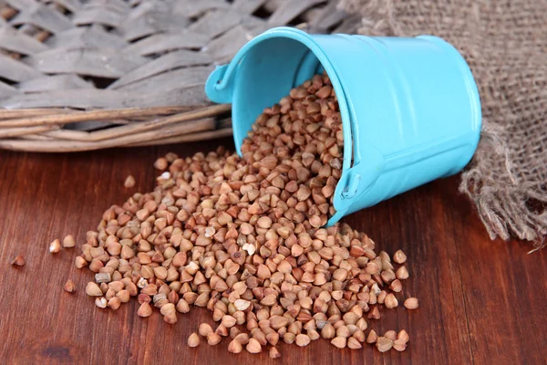 Overturned bucket with grains on wooden background — Stock Photo, Image