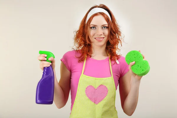 Jonge huisvrouw spuittoestel houden op grijze achtergrond — Stockfoto